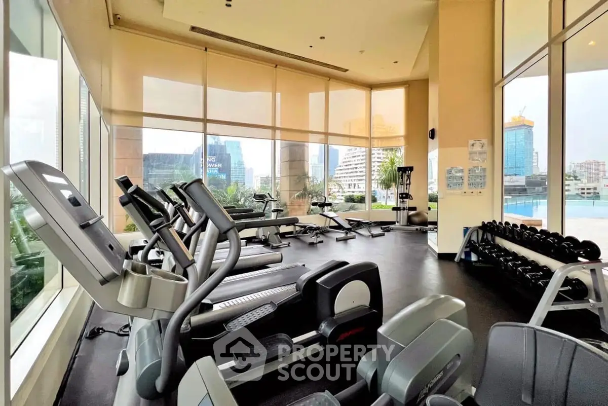 Spacious gym with modern equipment and city view in luxury building