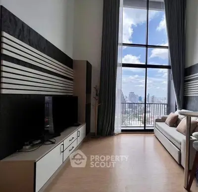 Spacious living room with floor-to-ceiling windows offering stunning city views and modern decor.
