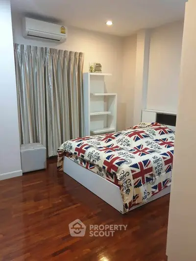 Cozy bedroom with wooden flooring and modern decor in a stylish apartment.