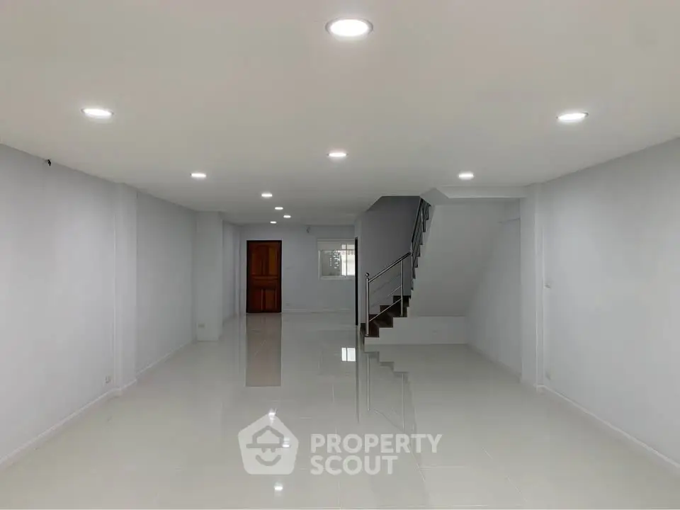 Spacious open-plan living area with modern lighting and sleek staircase, perfect for customization.