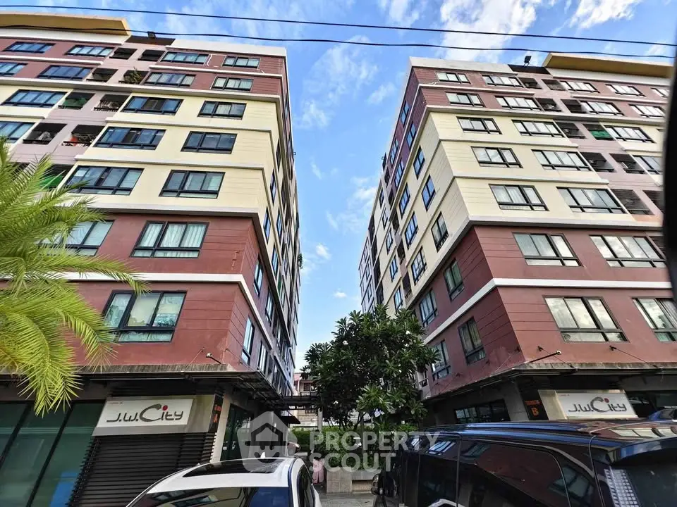 Modern apartment buildings with vibrant facade and lush greenery in urban setting.