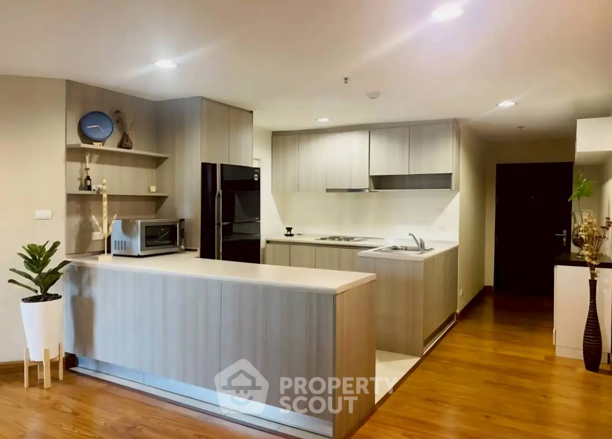 Modern kitchen with sleek cabinetry and wooden flooring in a stylish apartment.