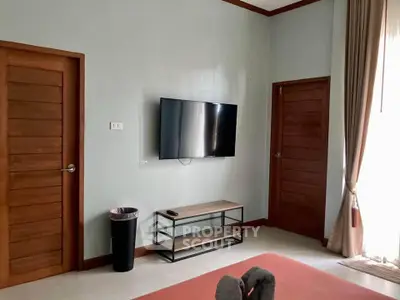 Cozy living room with wall-mounted TV and wooden doors, perfect for relaxation.