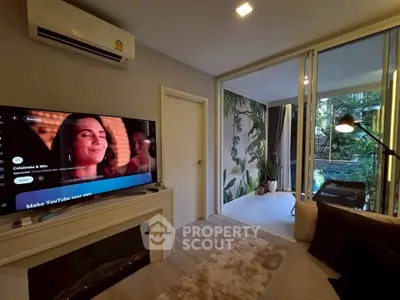 Stylish living room with modern decor and large TV, opening to a lush balcony view.