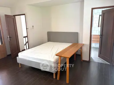 Spacious bedroom with modern bed and wooden flooring, adjacent to a stylish bathroom.
