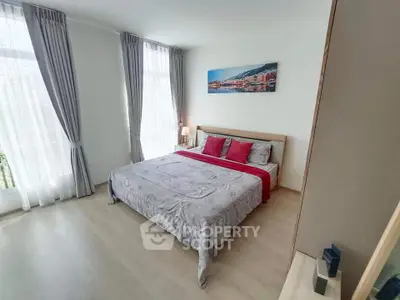 Spacious bedroom with large windows and elegant decor in modern apartment.