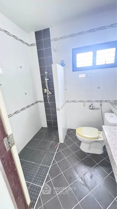 Modern bathroom with sleek tile design and natural light from window.