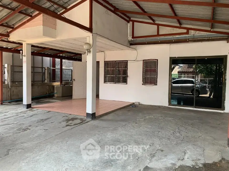 Spacious covered parking area with tiled section and sliding glass door.