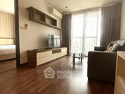 Modern living room with wooden flooring, sleek TV unit, and cozy sofa near large window.
