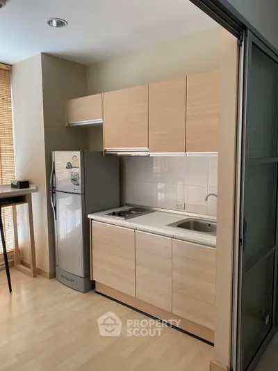 Modern compact kitchen with light wood cabinets and sleek appliances