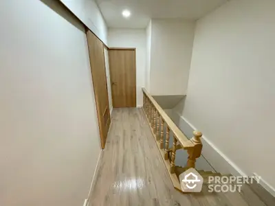 Modern staircase with wooden railing and sleek flooring in a bright hallway