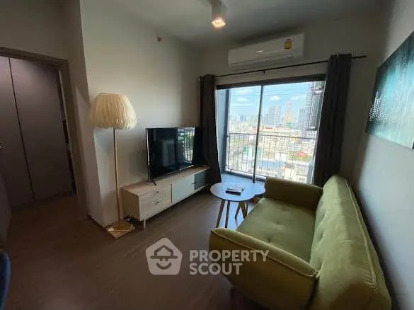Cozy living room with city view, featuring a green sofa, TV, and modern decor.