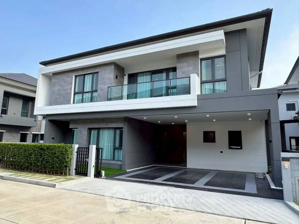 Modern two-story house with sleek design and spacious driveway in a suburban neighborhood.