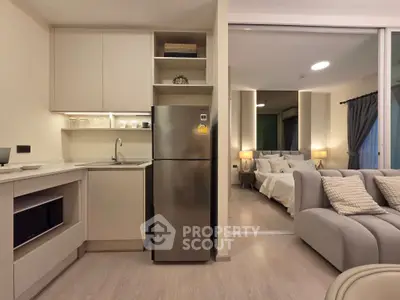 Modern open-plan living area with sleek kitchen and cozy bedroom view.