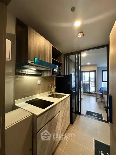 Modern compact kitchen with sleek cabinetry and open layout leading to living area.