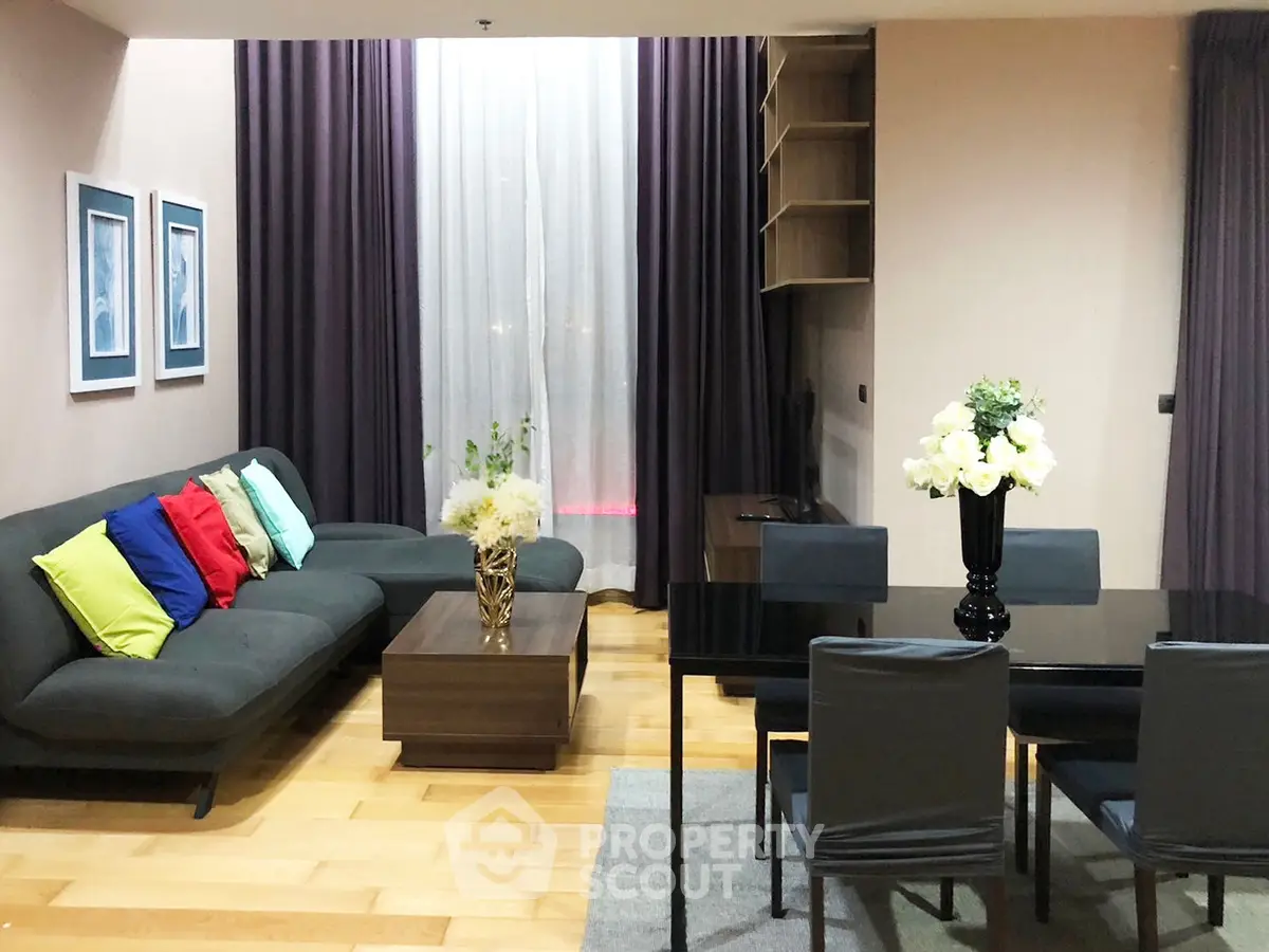 Modern living room with stylish decor and dining area, featuring hardwood floors and elegant curtains.