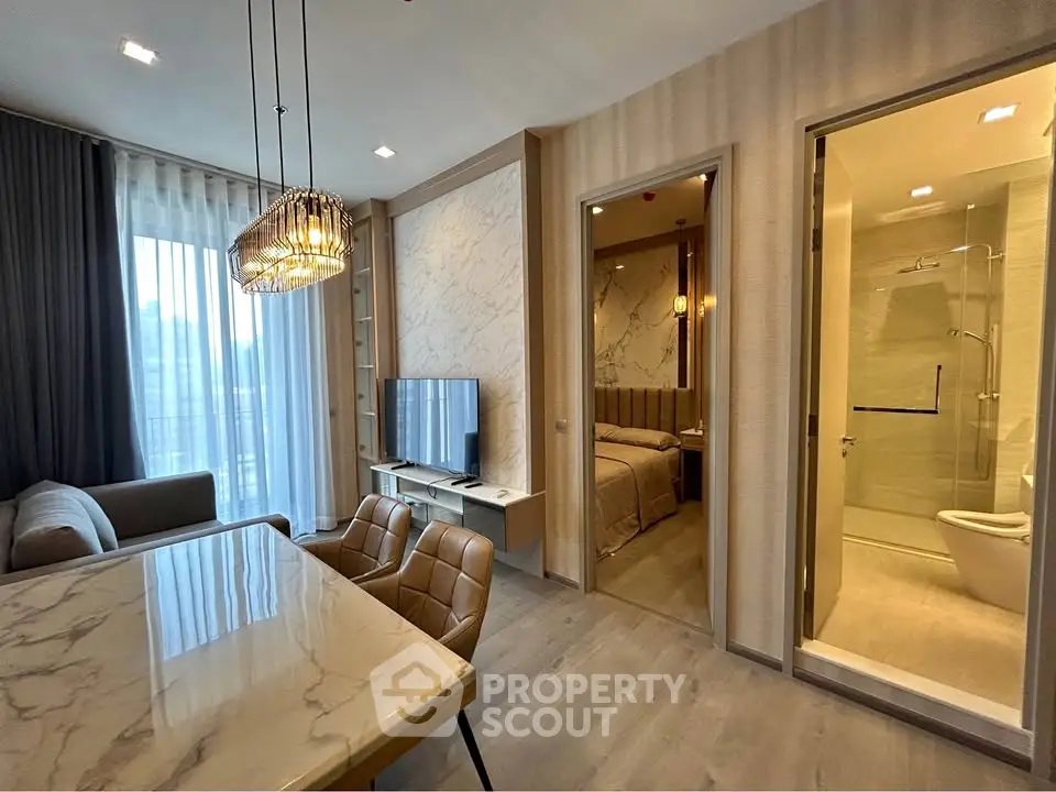 Modern open-plan living room with elegant dining area and view into bedroom and bathroom.