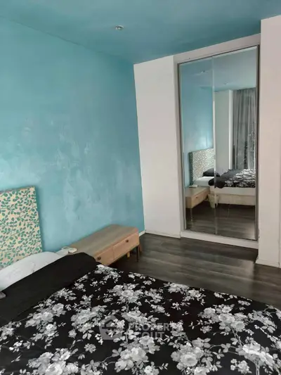 Charming bedroom with mirrored closet and floral bedding in modern apartment.