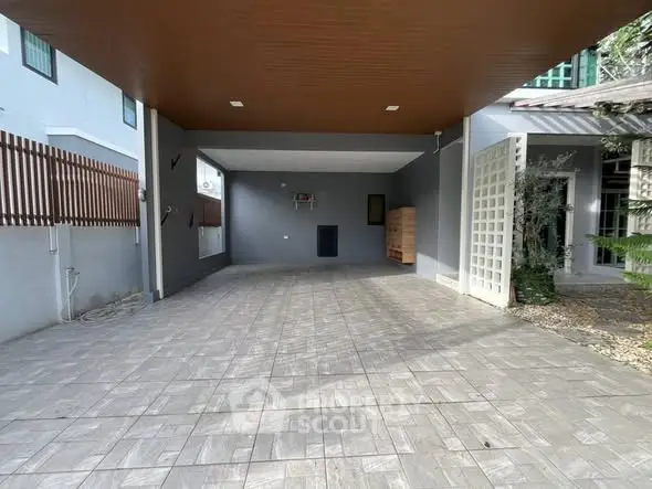 Spacious modern carport with tiled flooring and wooden ceiling in a contemporary home.