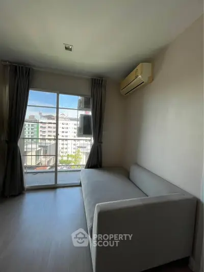 Modern living room with large window and city view, featuring a sleek sofa and air conditioning.