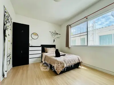 Bright and cozy bedroom with modern decor and large window view.