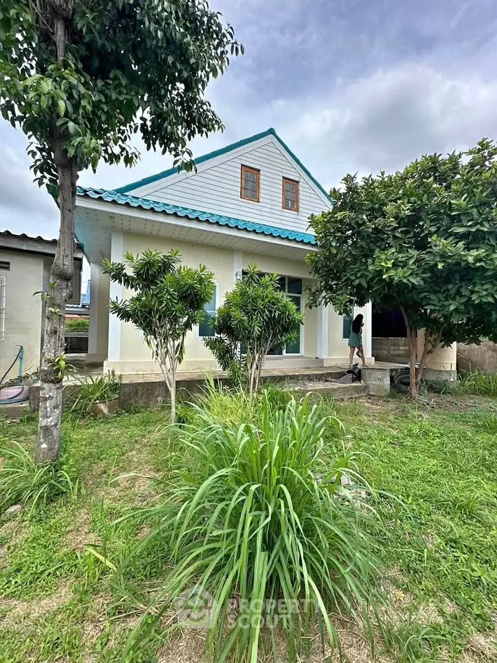 Charming single-story house with lush garden and blue roof, ideal for serene living.