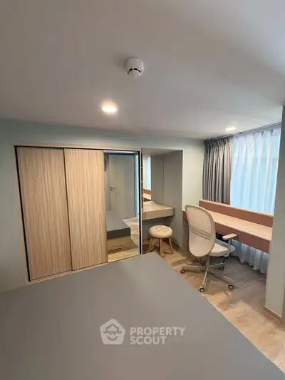Modern study room with sleek desk, comfortable chair, and ample natural light from large window.