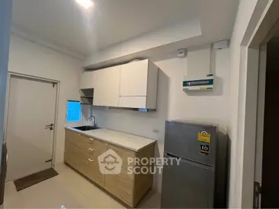 Modern kitchen with sleek cabinets and stainless steel fridge in a compact layout.