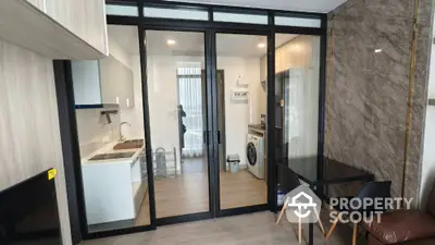 Modern apartment interior with glass partition, kitchen, and washing machine