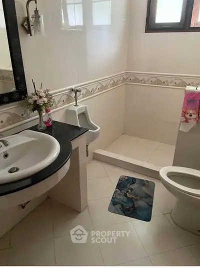 Spacious bathroom with elegant fixtures and decorative accents, featuring a urinal and stylish sink.