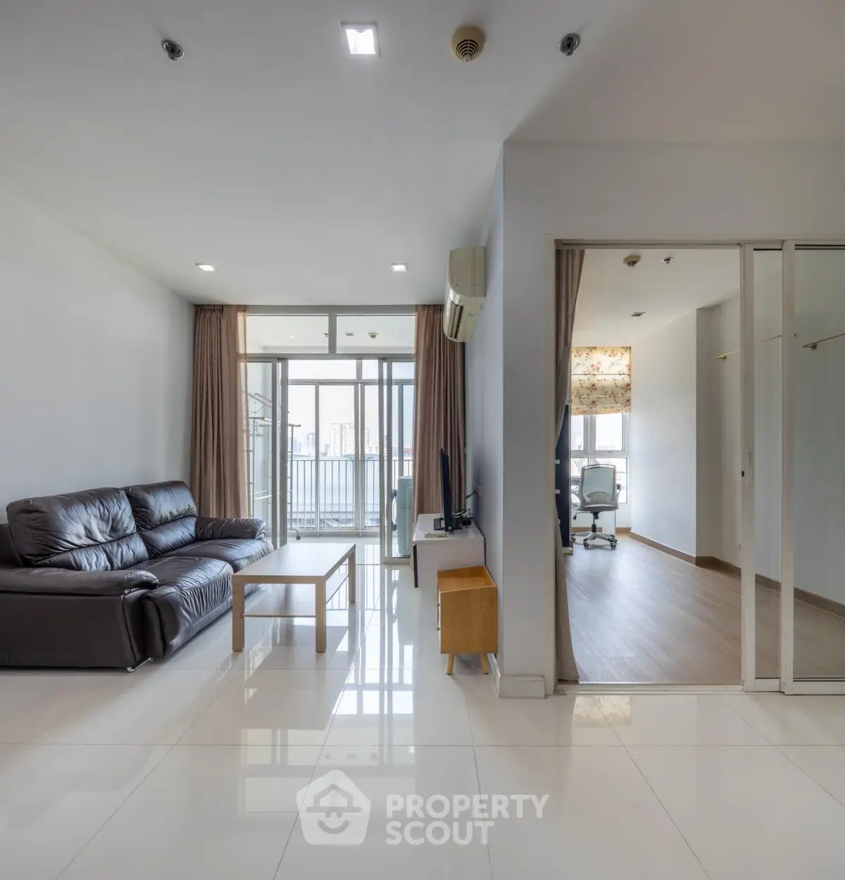 Spacious modern living room with leather sofa and balcony view