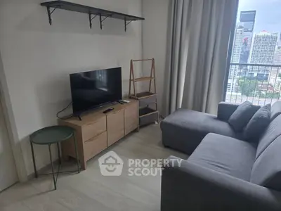 Modern living room with city view, featuring a sleek TV setup and comfortable gray sofa.