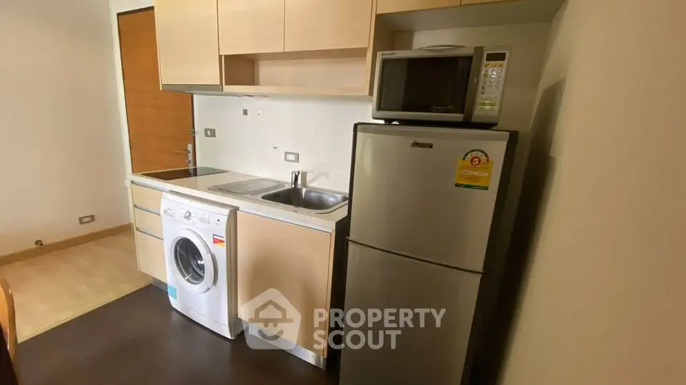 Compact kitchen with washing machine and fridge in modern apartment