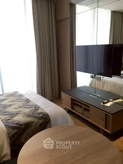Modern bedroom with stylish decor and wall-mounted TV, featuring elegant curtains and wooden furniture.