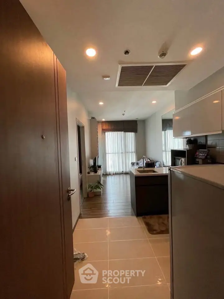 Modern apartment entrance leading to a cozy living area with natural light and stylish kitchen.