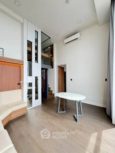 Modern living room with high ceiling and stylish decor, featuring a mezzanine and sleek air conditioning unit.