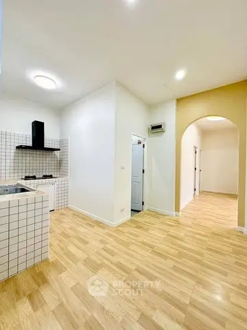 Spacious kitchen with modern gas stove and open layout, featuring elegant wooden flooring and bright lighting.