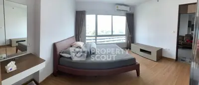 Spacious bedroom with large window and modern furnishings in a stylish apartment.