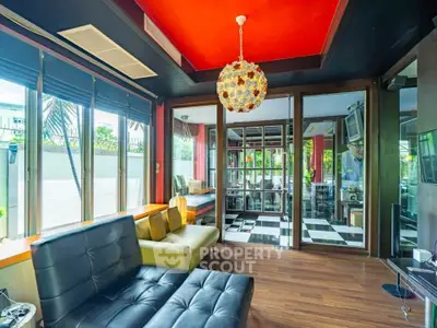 Stylish modern living room with vibrant red ceiling and unique lighting fixture.