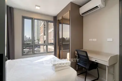 Modern bedroom with city view, featuring sleek furniture and ample natural light.
