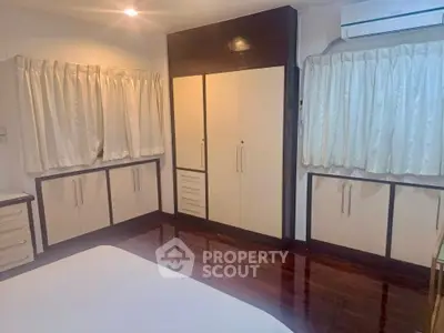 Spacious bedroom with elegant wooden flooring and ample storage space.