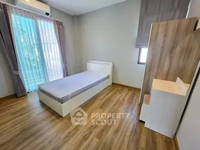 Modern minimalist bedroom with wooden flooring and ample natural light