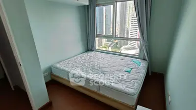 Bright bedroom with large window offering stunning city views, featuring a comfortable mattress and modern decor.