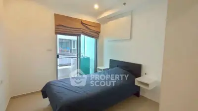 Cozy bedroom with modern design and balcony access in urban apartment.