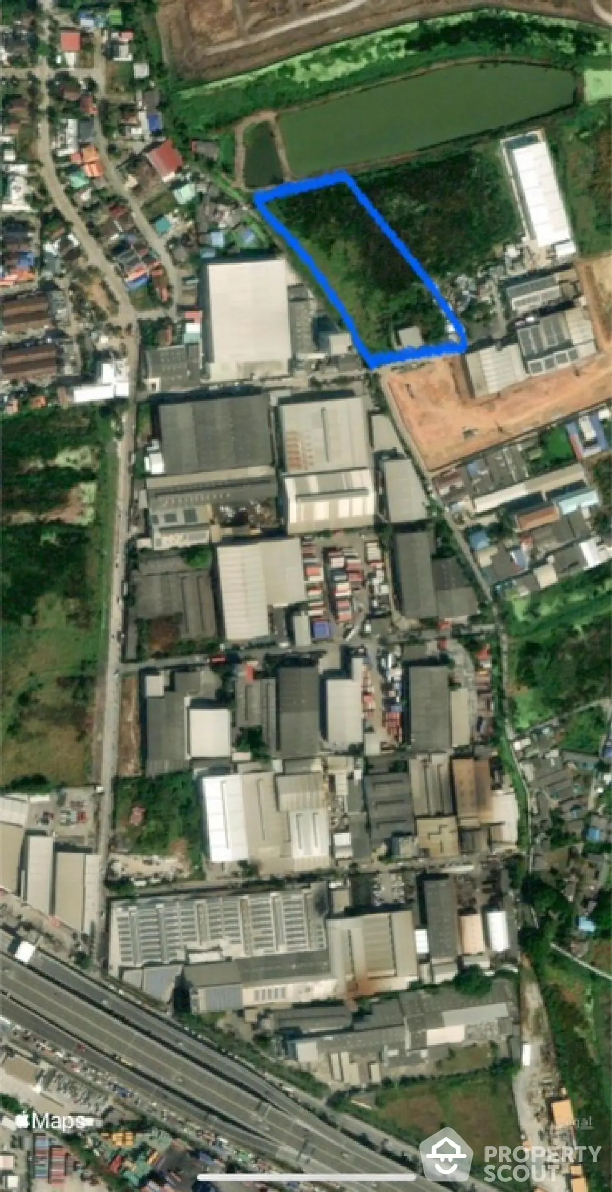 Aerial view of industrial area with marked land plot for development opportunities.