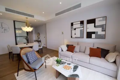 Modern living room with stylish decor and open dining area, featuring elegant furniture and contemporary art.
