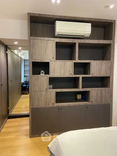 Modern bedroom with stylish built-in wooden shelving and air conditioning unit