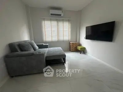 Modern living room with sleek furniture and wall-mounted TV, featuring a cozy sectional sofa and minimalist decor.