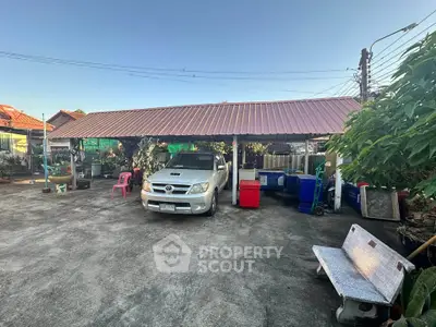 Spacious outdoor parking area with covered carport and garden view.