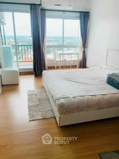 Spacious bedroom with large window offering stunning city views and natural light.